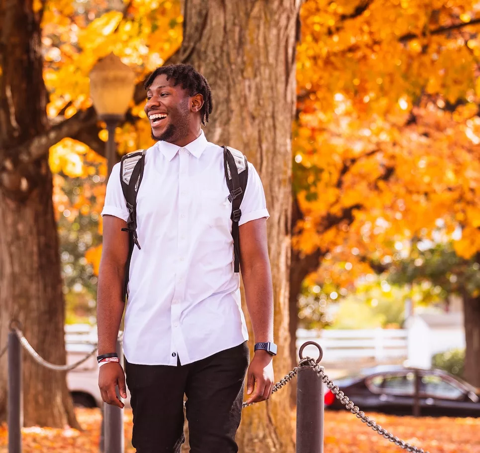 Student walking on campus in the fall.