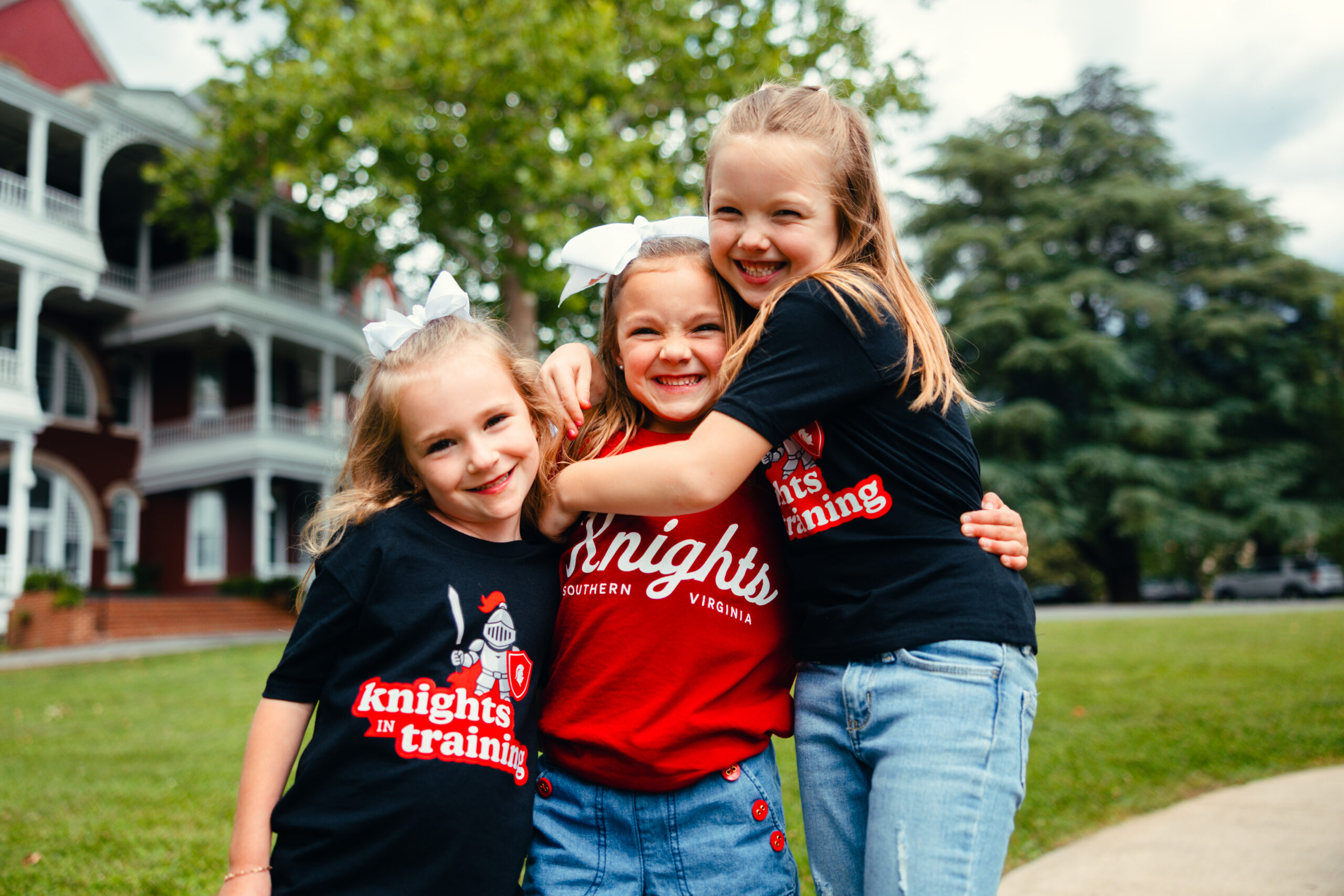 Smiling young girls hug in front of an ornate red building
