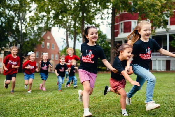 Children wearing SVU shirts run across the grass